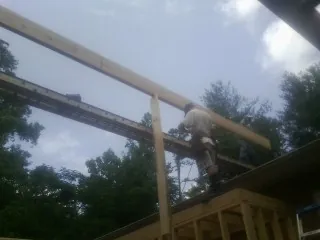 Carpenter setting a ridge beam over a new addition frame — Ice Dam Removal by Roofing Brothers in Martins Creek