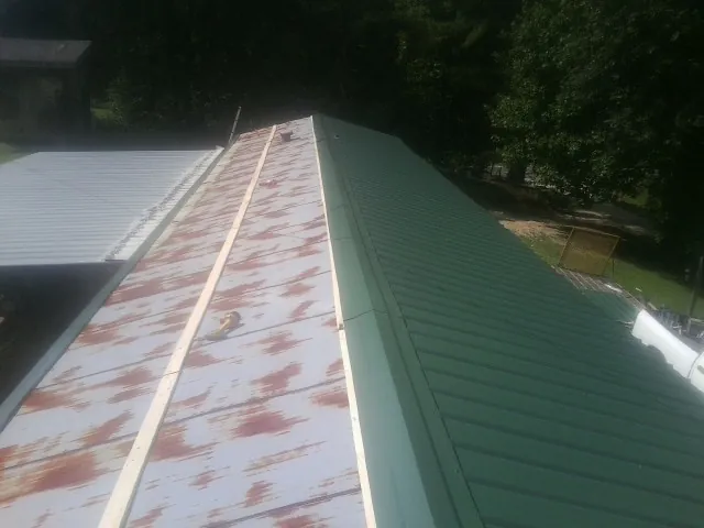 Old rusted panels beside newly installed green metal roofing — Wind Damage Roof Repair by Roofing Brothers in Martins Creek