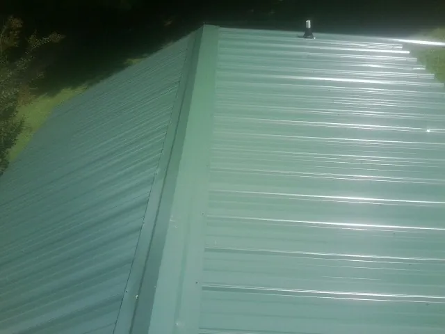 New green metal panels meeting at the ridge of a roof — Flat Roof Repair work by our crew in Martins Creek