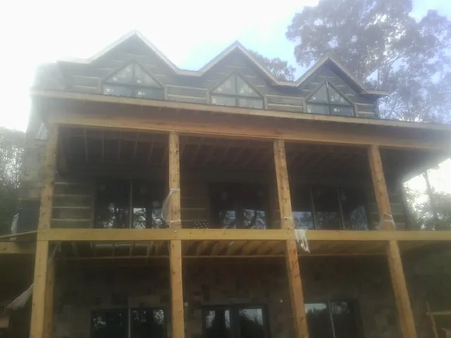 Dormers and porch framing on a large log home under construction — Roof Coating work by our crew in Martins Creek