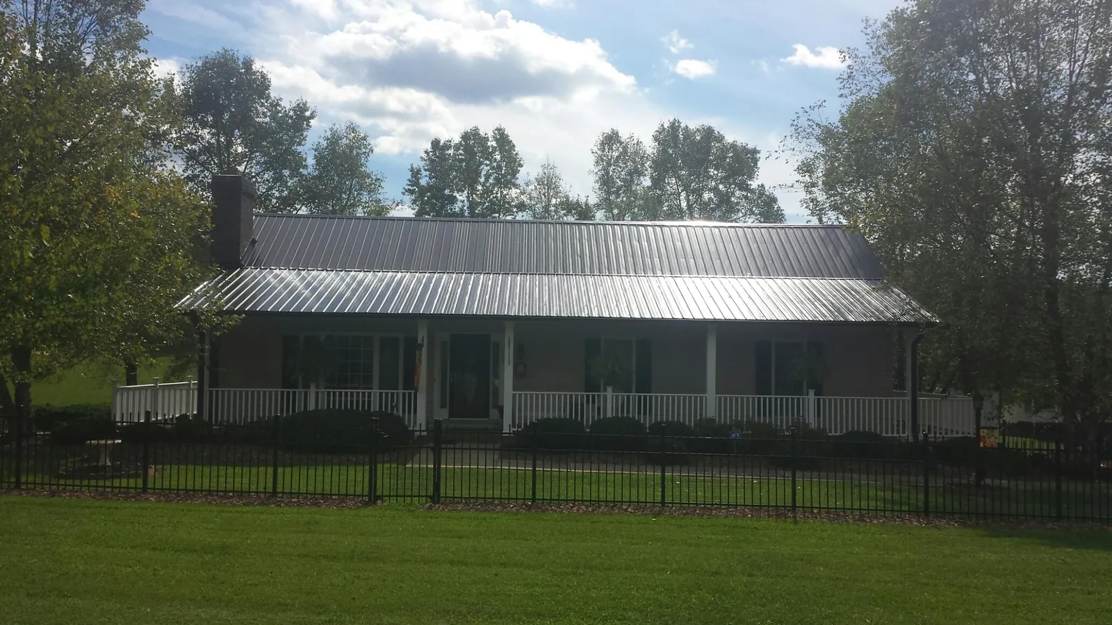 Gray metal roof on a brick ranch with a full width front porch — Gutter Guard Installation work by our crew in Martins Creek