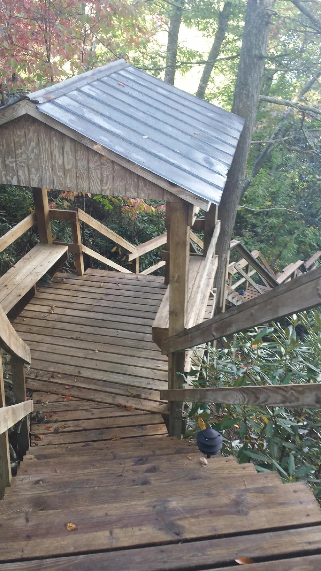 Metal roofed shelter over wooden steps on a wooded walkway — Skylight Repair & Installation work by our crew in Martins Creek