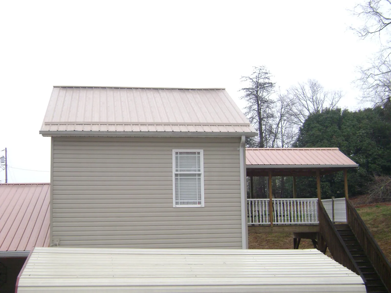 Tan metal roofs on a two story addition and attached porch, from a Roof Replacement job in Martins Creek