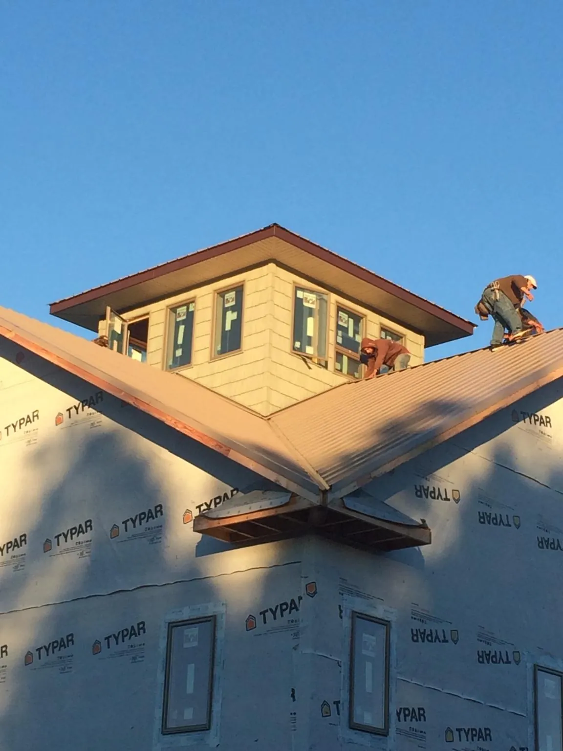 Roofers working around a rooftop cupola on a new metal roof at sunset — Roof Waterproofing in Martins Creek by Roofing Brothers